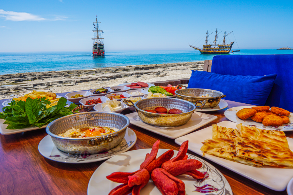 Tyrkisk morgenmad på Ulas Heaven Beach, traditionel morgenmad ved stranden i Alanya, Ulas strand oplevelser, autentisk tyrkisk kahvaltı med havudsigt, morgenmad med lokale specialiteter på Heaven Beach, hyggelig start på dagen i Alanya, strandrestaurant med tyrkisk stemning, seværdighed for madelskere i Alanya, afslapning og smag ved Middelhavet, tyrkisk morgenmad i naturskønne omgivelser, Ulas Heaven Beach Alanya.