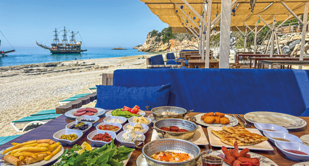 Tyrkisk morgenmad på Ulas Heaven Beach, traditionel morgenmad ved stranden i Alanya, Ulas strand oplevelser, autentisk tyrkisk kahvaltı med havudsigt, morgenmad med lokale specialiteter på Heaven Beach, hyggelig start på dagen i Alanya, strandrestaurant med tyrkisk stemning, seværdighed for madelskere i Alanya, afslapning og smag ved Middelhavet, tyrkisk morgenmad i naturskønne omgivelser, Ulas Heaven Beach Alanya.
